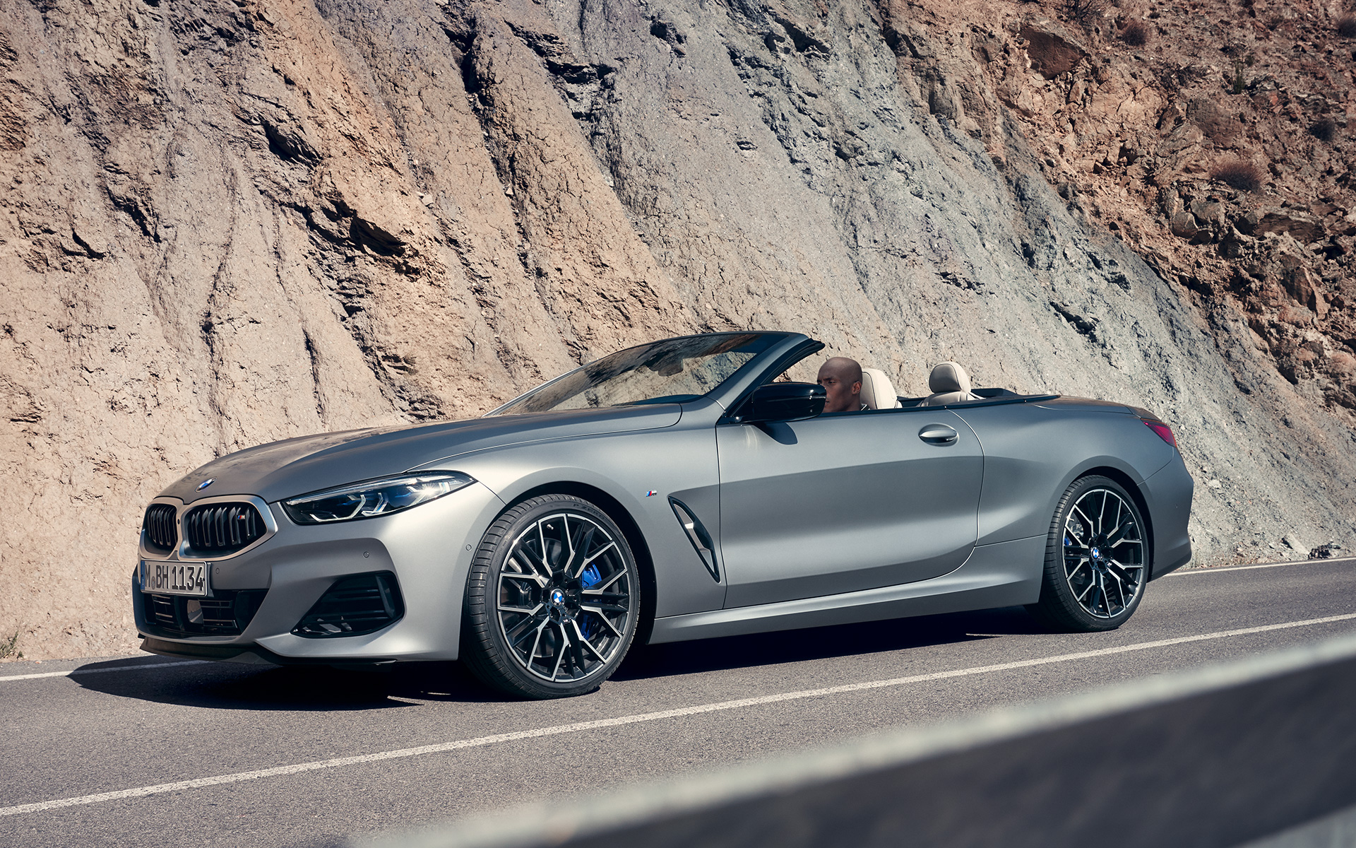 BMW M850i xDrive Cabrio G14 LCI Facelift 2022, BMW Individual Морозный Чистый Серый металлик, вид спереди в три четверти в движении на фоне скалы