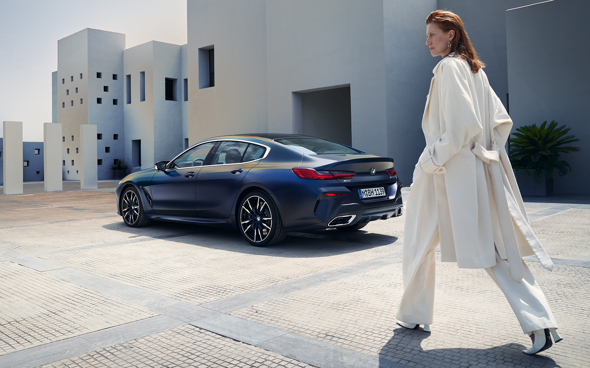 BMW M850i xDrive Gran Coupe G16 LCI Facelift 2022, BMW Individual Морозный Синий Танзанит металлик, вид сзади в три четверти с женщиной